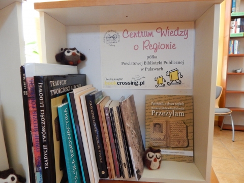 Zdjęcie prezentuje półkę Bookcrossingową pod nazwą „Centrum  wiedzy o regionie” znajdującą się w Powiatowej Bibliotece Publicznej w Puławach. Głównym celem półki jest wymiana publikacji regionalnych i umożliwienie dotarcia do wydawnictw powiatowych szerszemu gronu odbiorców.