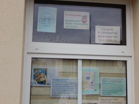 Zdjęcie prezentuje wystawę na oknach Powiatowej Biblioteki Publicznej w Puławach pokazującą książki promujące zdrowe odżywanie wśród najmłodszych. 