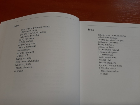 Zdjęcie prezentuje położoną na stoliku książkę pt. „Godko mojo” autorstwa Zbigniewa Kozaka otwartą na wierszu „Zycie”.