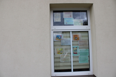 Zdjęcie prezentuje wystawę na oknach Powiatowej Biblioteki Publicznej pokazującą książki dla dzieci, których akcja rozgrywa się właśnie w bibliotece. 
