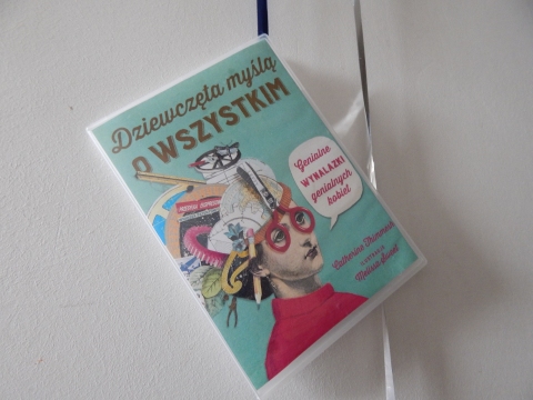 Zdjęcie prezentuje wystawę powieszoną na korytarzu przed biblioteką prezentującą różne okładki książek o inteligentnych, odważnych i silnych kobietach.
