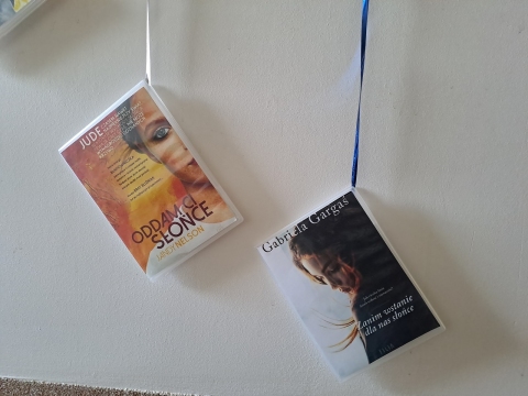 Zdjęcie prezentuje wystawę powieszoną na korytarzu przed biblioteką prezentującą różne okładki książek z wyrazem słońce w tytule.