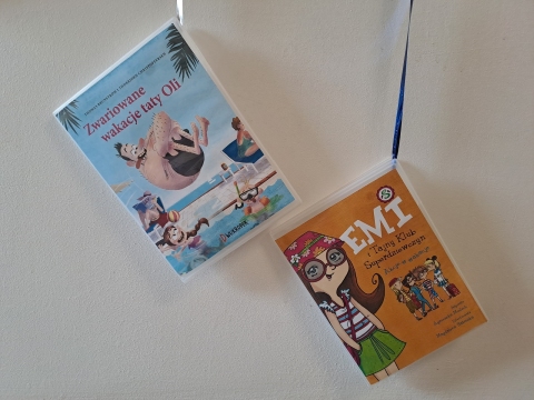 Zdjęcie prezentuje wystawę na oknach Powiatowej Biblioteki Publicznej w Puławach pokazującą książki, których akcja dzieje się nad morzem, w górach i na Mazurach.