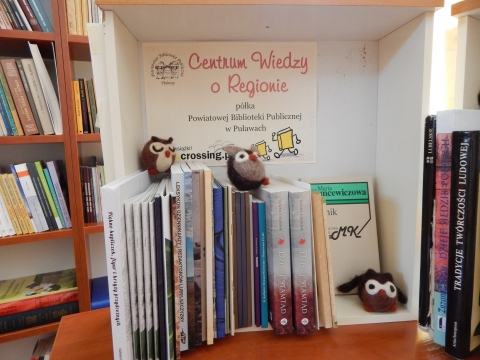 Zdjęcie prezentuje półkę Bookcrossingową pod nazwą „Centrum  wiedzy o regionie” znajdującą się w Powiatowej Bibliotece Publicznej w Puławach. Głównym celem półki jest wymiana publikacji regionalnych i umożliwienie dotarcia do wydawnictw powiatowych szerszemu gronu odbiorców.