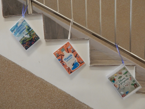 Zdjęcie prezentuje wystawę powieszoną na korytarzu przed biblioteką prezentującą różne okładki książek dla dzieci promujących ochronę środowiska i ekologiczne działania na rzecz naszej planety.