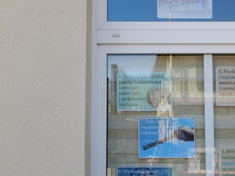 Wystawa na oknach biblioteki prezentująca 25 powodów dla których warto odwiedzić bibliotekę