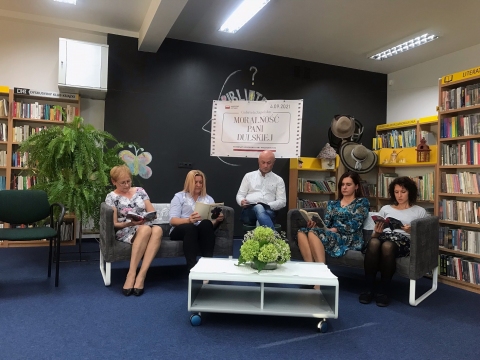 Zdjęcie prezentuje osoby czytające fragmenty dramatu "Moralność Pani Dulskiej" Gabrieli Zapolskiej w siedzibie biblioteki.