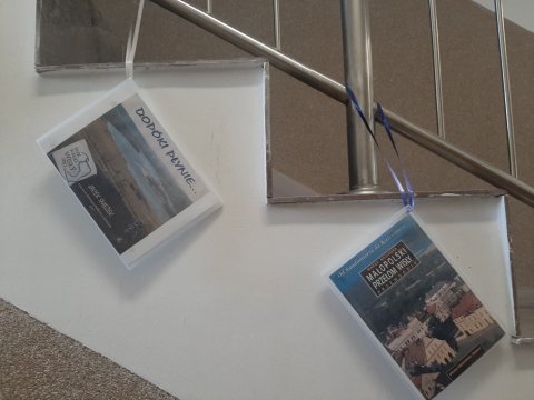 Zdjęcie prezentuje wystawę powieszoną na korytarzu przed biblioteką prezentującą różne okładki książek poświęconych rzece Wiśle. 