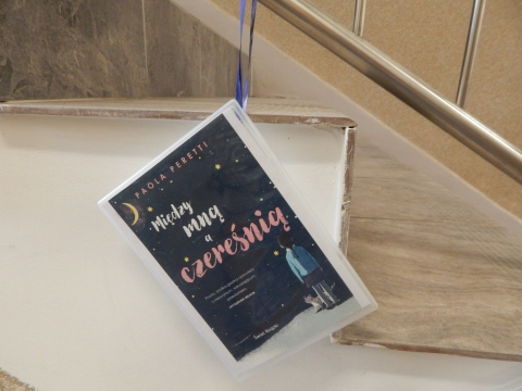 Zdjęcie prezentuje wystawę powieszoną na korytarzu przed biblioteką prezentującą różne okładki książek ze smakiem owoców  tytule.