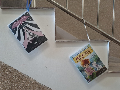 Zdjęcie prezentuje wystawę na oknach Powiatowej Biblioteki Publicznej w Puławach pokazującą książki, których akcja dzieje się nad morzem, w górach i na Mazurach.