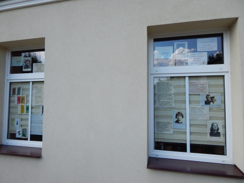 Zdjęcie prezentuje wystawę na oknach Powiatowej Biblioteki Publicznej w Puławach pokazującą życie i twórczość Wisławy Szymborskiej. 