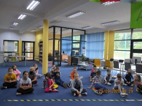 Zdjęcie prezentujące dzieci, uczestników Ogólnopolskiego Dnia Głośnego Czytania w bibliotece gminy Puławy. Pani bibliotekarka czyta przedszkolakom opowiadanie. 