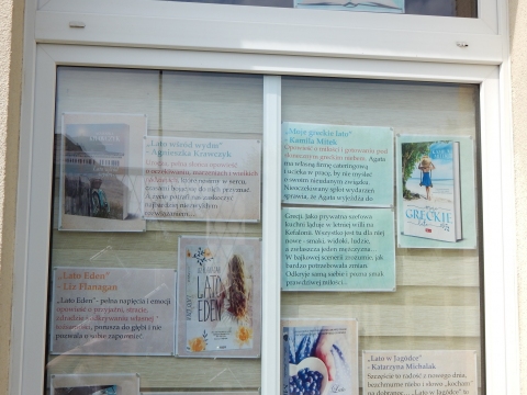 Zdjęcie prezentuje wystawę na oknach Powiatowej Biblioteki Publicznej w Puławach pt. „Książki z latem w tle”.