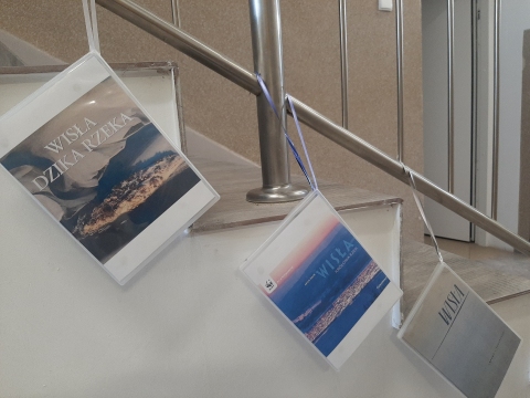 Zdjęcie prezentuje wystawę powieszoną na korytarzu przed biblioteką prezentującą różne okładki książek poświęconych rzece Wiśle. 