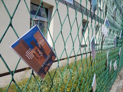 Zdjęcie przedstawia wystawę okładek książkę Stanisława Lema, które zawisły na płocie przed PBP w Puławach. 