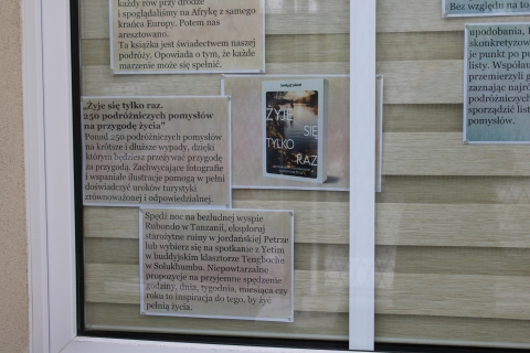 Zdjęcie prezentuje wystawę na oknach Powiatowej Biblioteki Publicznej prezentującą ciekawe książki o tematyce podróżniczej.