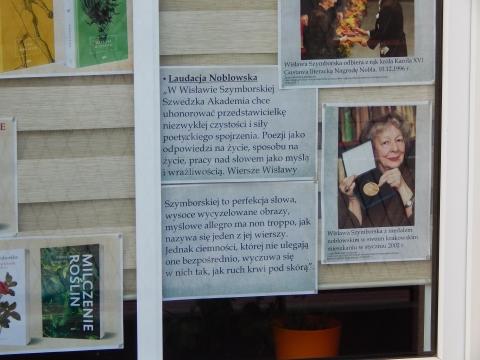 Zdjęcie prezentuje wystawę na oknach Powiatowej Biblioteki Publicznej w Puławach pokazującą życie i twórczość Wisławy Szymborskiej. 