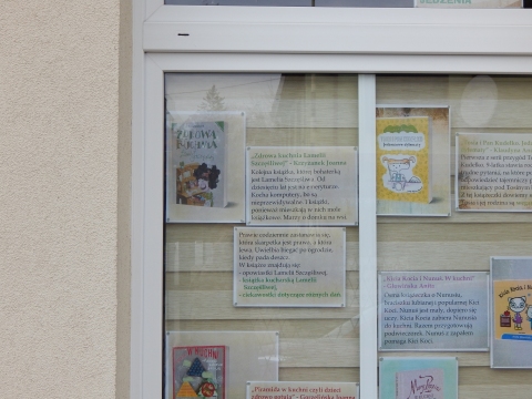Zdjęcie prezentuje wystawę na oknach Powiatowej Biblioteki Publicznej w Puławach pokazującą książki promujące zdrowe odżywanie wśród najmłodszych. 