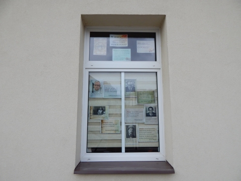 Zdjęcie prezentuje wystawę na oknach Powiatowej Biblioteki Publicznej w Puławach pokazującą różne definicje słowa poezja. 