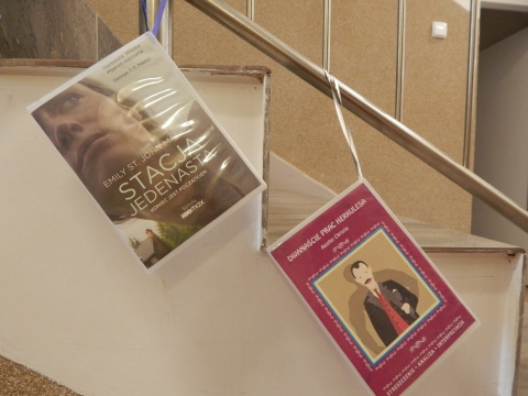 Zdjęcie prezentuje wystawę powieszoną na korytarzu przed biblioteką prezentującą różne okładki książek ze numerem tytule.