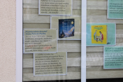Zdjęcie prezentuje wystawę na oknach Powiatowej Biblioteki Publicznej pokazującą książki dla dzieci, których akcja rozgrywa się właśnie w bibliotece. 