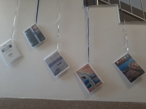 Zdjęcie prezentuje wystawę powieszoną na korytarzu przed biblioteką prezentującą różne okładki książek poświęconych rzece Wiśle. 