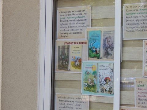 Zdjęcie prezentuje wystawę na oknach Powiatowej Biblioteki Publicznej w Puławach poświęconą życiu i twórczości Marii Konopnickiej.