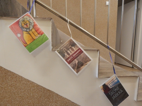 Zdjęcie prezentuje wystawę powieszoną na korytarzu przed biblioteką prezentującą różne okładki książek ze smakiem owoców  tytule.