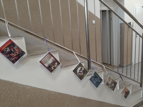 Zdjęcie prezentuje wystawę powieszoną na korytarzu przed biblioteką prezentującą różne okładki książek, w których ważna rolę odgrywają kobiety. 