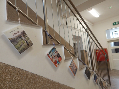 Zdjęcie prezentuje wystawę powieszoną na korytarzu przed biblioteką prezentującą różne okładki książek autorstwa Bolesława Prusa. 