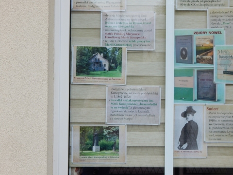 Zdjęcie prezentuje wystawę na oknach Powiatowej Biblioteki Publicznej w Puławach poświęconą życiu i twórczości Marii Konopnickiej.