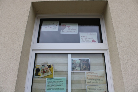 Zdjęcie prezentuje wystawę na oknach Powiatowej Biblioteki Publicznej w Puławach prezentującą książki o miłości dla dzieci i młodzieży.