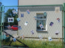 Zdjęcie przedstawia wystawę okładek książkę Stanisława Lema, które zawisły na płocie przed PBP w Puławach. 