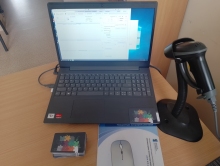 Zdjęcie prezentuje stojący na stole otwarty laptop na którym widać uruchomiony program biblioteczny Prolib, obok niego stroi czetnik kodów kreskowych i leży karta biblioteczna do sieci bibliotek powiatu puławskiego.  