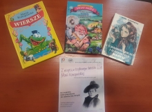 Zdjęcie przedstawia ułożone na stoliku książki autorstwa Marii Konopnickiej i plakat zachęcający do wzięcia udziału w powiatowym konkursie plastycznym pt. „Z wizytą w bajkowym świecie Marii Konopnickiej”.